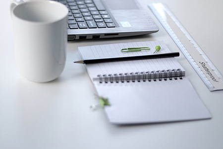 pencil on notebook beside a mug and laptop on talbe thumbnail