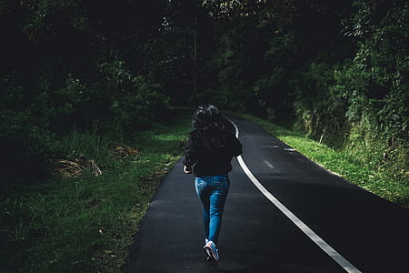 woman running on road between trees thumbnail