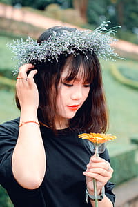 Woman Wearing Black Shirt Holding Yellow Petaled Flower Outside thumbnail