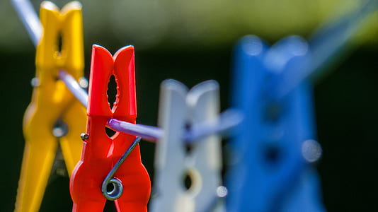 macrophotograph of red, blue, white, and yellow clothespin hanging on wire thumbnail