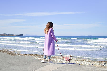 woman with her dog standing on seashore thumbnail