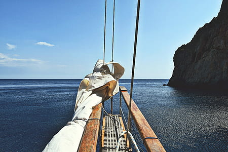 brown wooden sailboat near rock cliff thumbnail