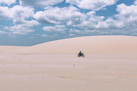 person riding black motorcycle on sand under cloudy sky during daytime thumbnail