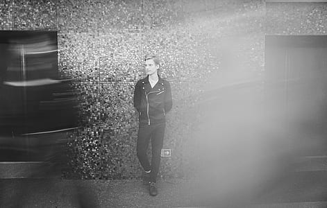 grayscale photo of man leaning on wall thumbnail