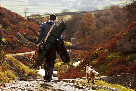 man with black bag walking with a short-coated white and brown dog thumbnail