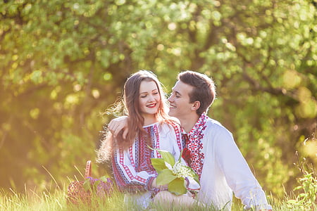 woman and man sitting on green grass field during daytime thumbnail