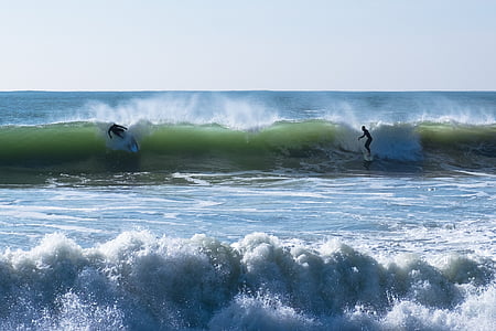 two person surfing on body of water during daytime thumbnail