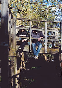 man and woman sitting on brown wooden bridge thumbnail