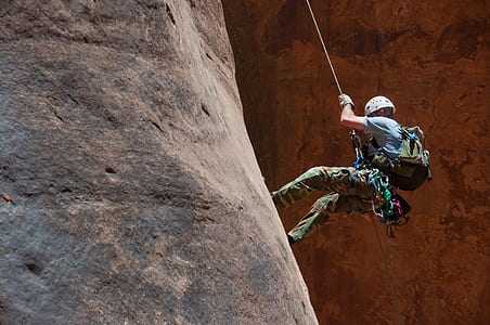 man hiking down on brown rock thumbnail