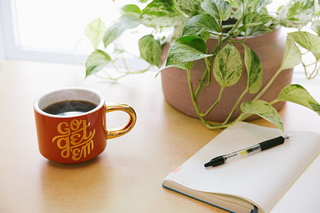 red coffee mug beside white notebook thumbnail