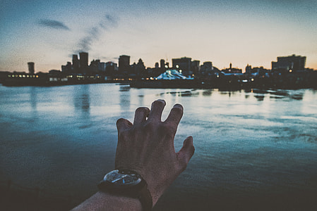 illusion of person grabbing cityscape while wearing black analog watch thumbnail