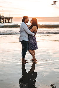 man and woman standing on seaside during sunset thumbnail