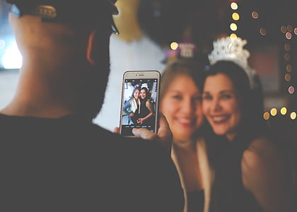 man taking a photo of two woman in room thumbnail