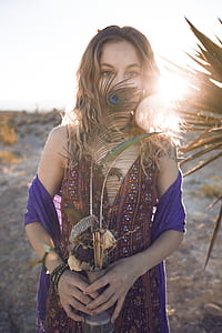 woman holding pot with peafowl feather covering her mouth thumbnail