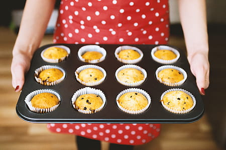 A young lady in a beautiful red apron just baked muffins thumbnail