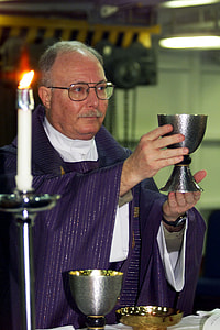 priest holding cup near candle thumbnail