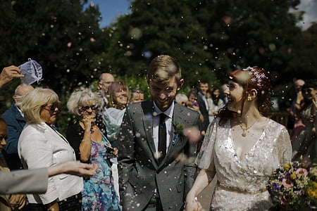 smiling bride and groom surrounded by guests during daytime thumbnail