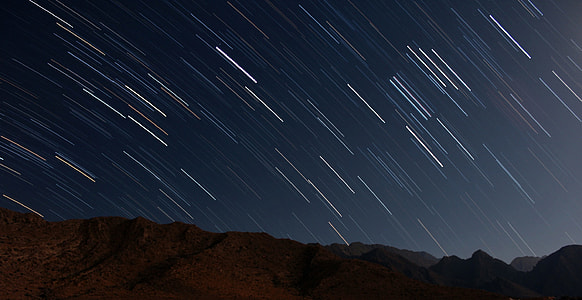 Star trails over the mountains in night sky thumbnail