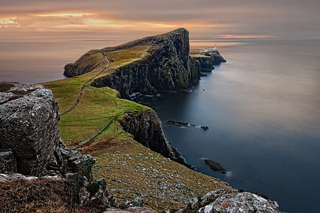 photography of mountain cliff beside seashore at daytime thumbnail