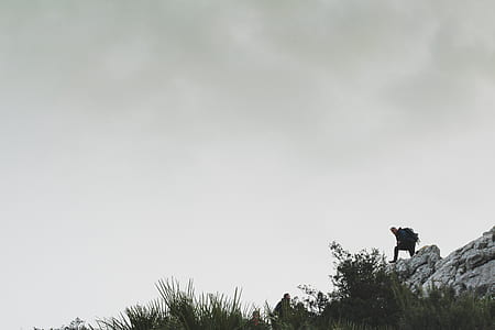 Person on Rocky Mountain Under White Cloudy Sky thumbnail
