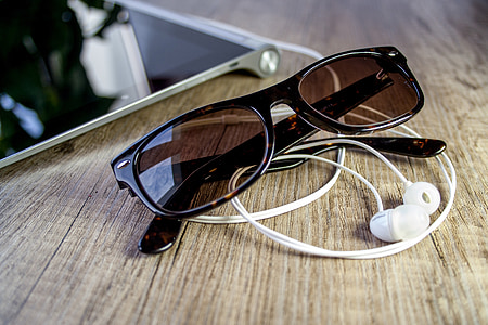 Wayfarer sunglasses near canalbuds on wooden surface thumbnail