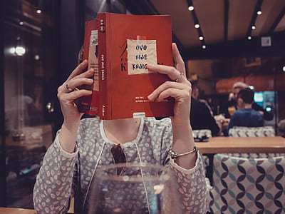 woman holding book sitting near to table thumbnail