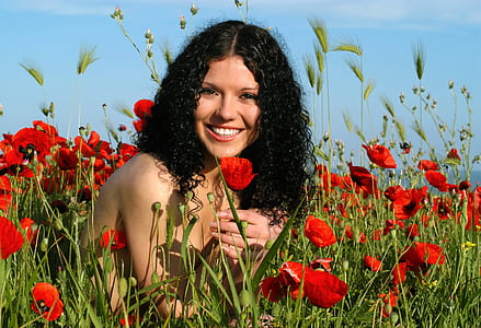 woman sitting near red poppy flower field thumbnail