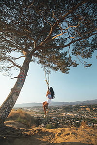 woman in white shorts hanging on gray rope during daytime thumbnail