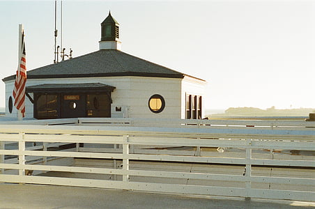 white and brown painted house near ocean under cloudy sky at daytime thumbnail