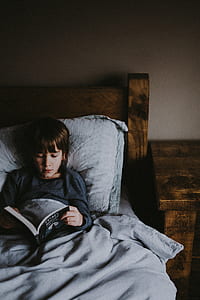 girl lying on bed reading book thumbnail