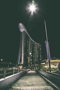 gray concrete pathway near to black and silver building during nighttime thumbnail