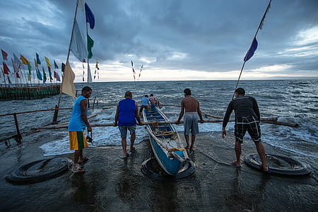 Four Person Pushing Boat Off Shore thumbnail