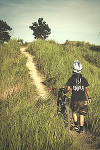 Man in Black Shirt and Brown Shorts Holding Bicycle thumbnail