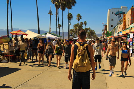 man carrying yellow backpack in front of pathway during daytime thumbnail