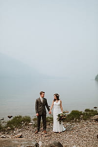 couple wedding standing beside body of water thumbnail