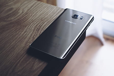 Black Samsung Android Smartphone on Top of Brown Wooden Tablke thumbnail