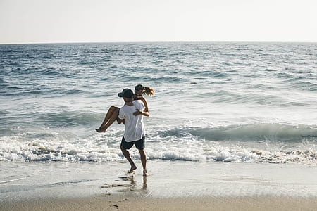 man carrying woman beside of the beach thumbnail