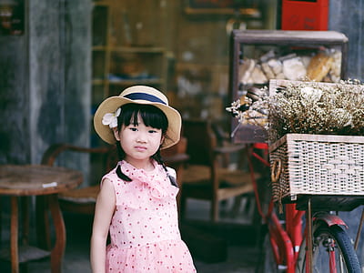 girl wearing pink dress standing beside red bike thumbnail
