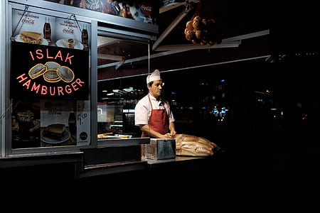 chef standing in gray food kiosk during nighttime thumbnail