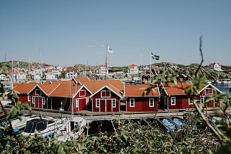 red and brown house besides white and blue boats under blue sky at daytime thumbnail