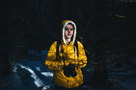 man in yellow hoodie carrying black DSLR camera thumbnail
