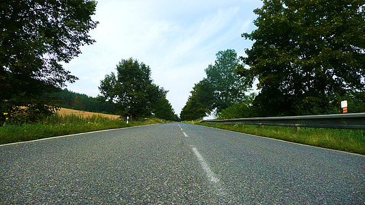 road between grass and trees at daytime thumbnail