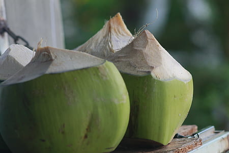 close-up photography of four green coconut fruits on brown wooden surface thumbnail