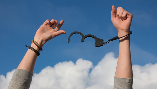 person freeing a handcuff with a view of blue sky thumbnail