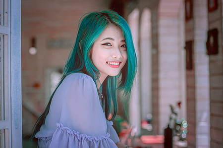woman smiling while standing near white wooden window thumbnail