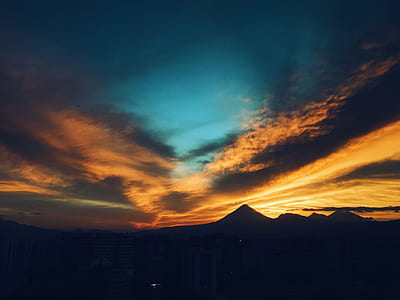 landscape photography of silhouette of mountains under blue and orange sky thumbnail