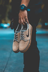 Person Holding Pair of Brown Nike Sneakers thumbnail