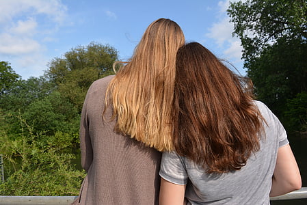 woman wearing gray shirt standing beside woman wearing brown jacket thumbnail