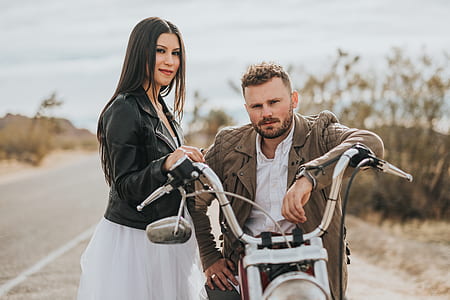 man sitting on motorcycle beside woman wearing black jacket thumbnail