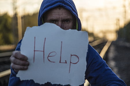 man wearing blue hooded jacket holding white printer paper with Help text label thumbnail